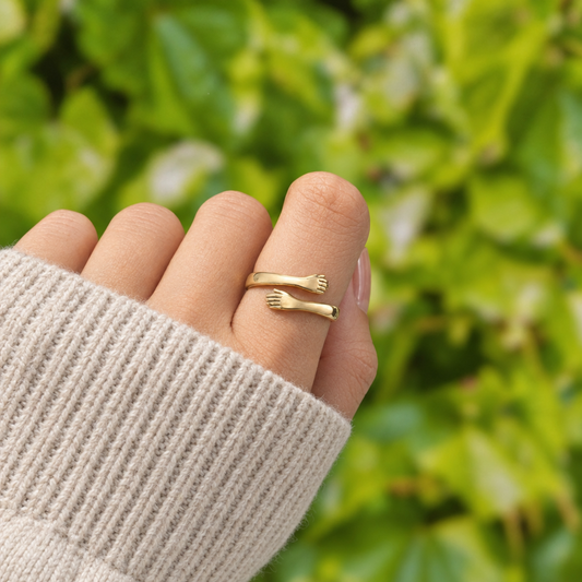 The gold hug ring worn on her finger, knit sleeve, garden background