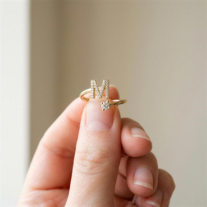 Gold initial ring with a paved letter M held between two fingertips