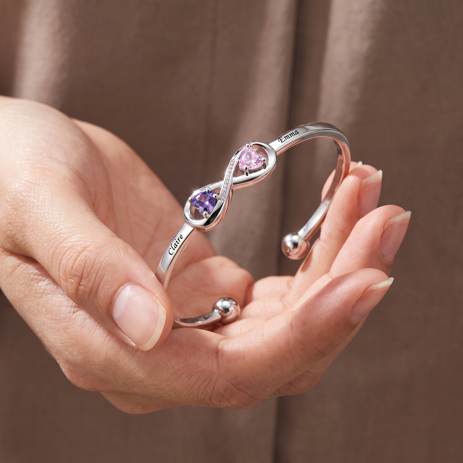 Infinity bangle with heart birthstones held in two hands