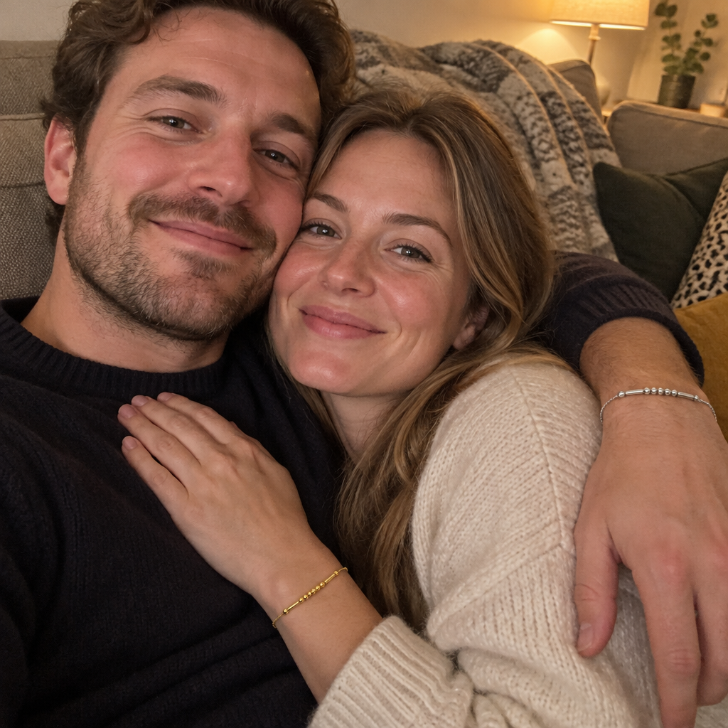 A couple on the sofa, gold Morse code bracelet on her wrist and silver on his