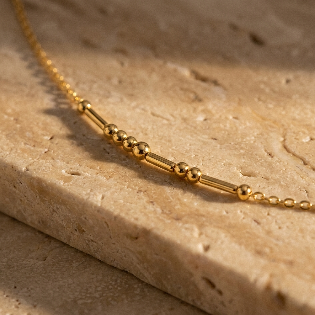 Close-up of the round gold beads and slim gold bars on the fine cable chain