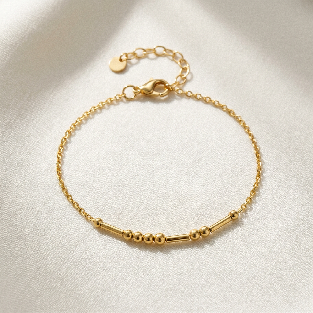 The gold Morse code bracelet on ivory fabric