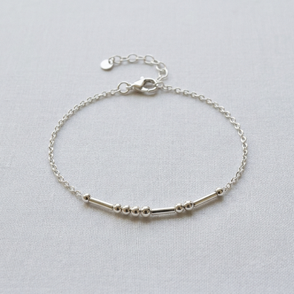 The silver Morse code bracelet on pale linen