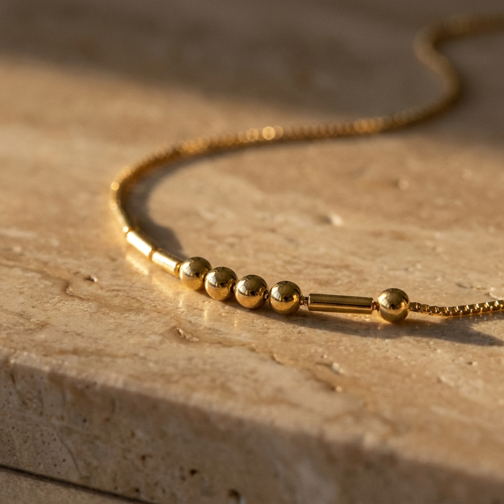 Close-up of the round gold beads and slim gold bars on the fine box chain