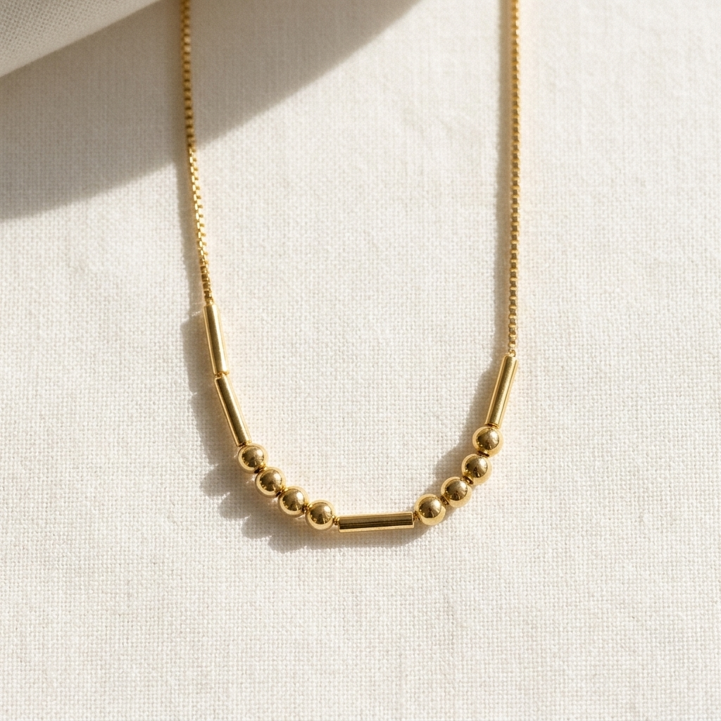 The gold Morse code necklace on ivory linen