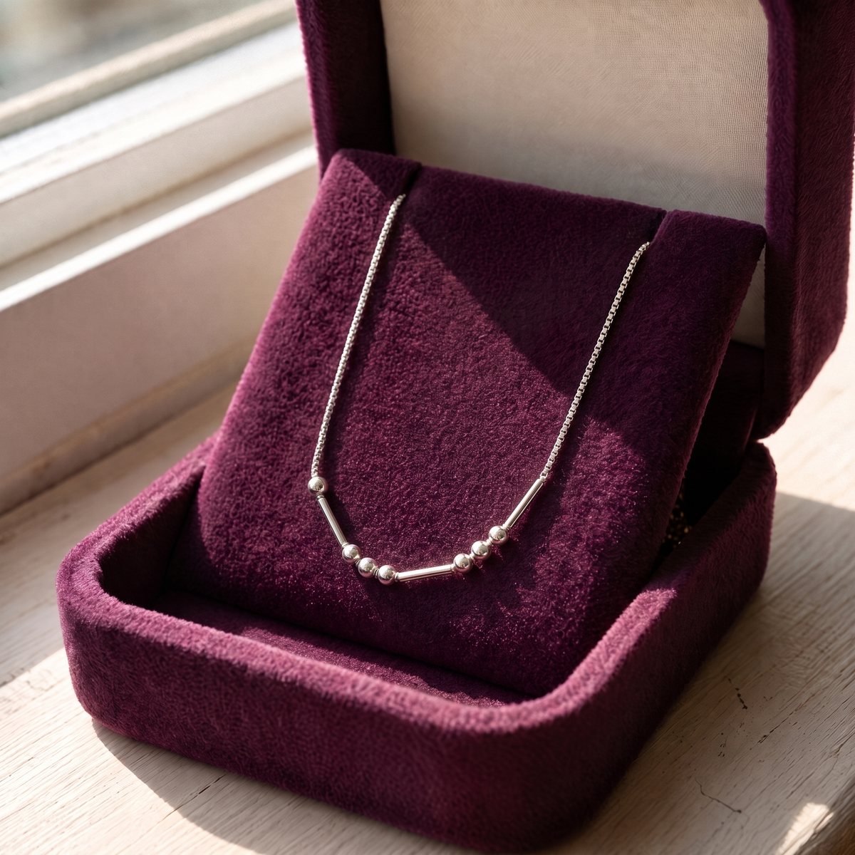The silver Morse code necklace in a plum velvet gift box