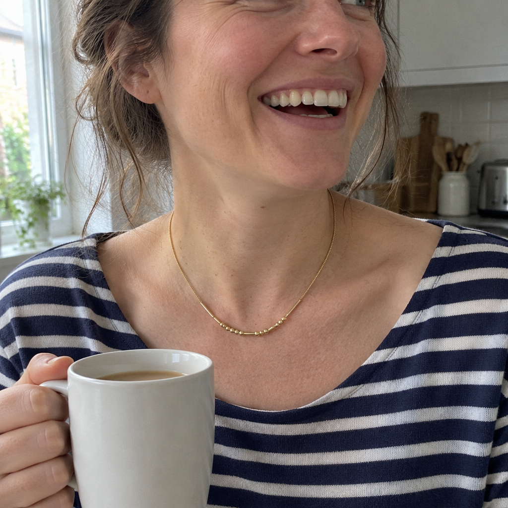 Her gold Morse code necklace, laughing in the kitchen with a mug of tea