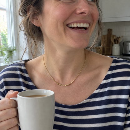 Her gold Morse code necklace, laughing in the kitchen with a mug of tea