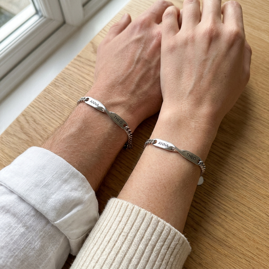 His wrist and her wrist side by side on an oak table, each wearing a matching name bracelet