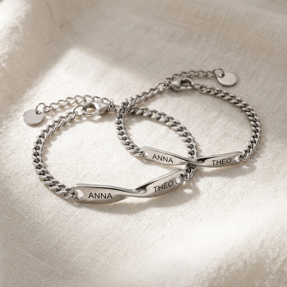 Two matching silver steel name bracelets on soft linen, packshot
