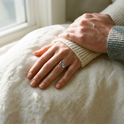 Her hand wearing the two-birthstone ring, his hand resting on her wrist