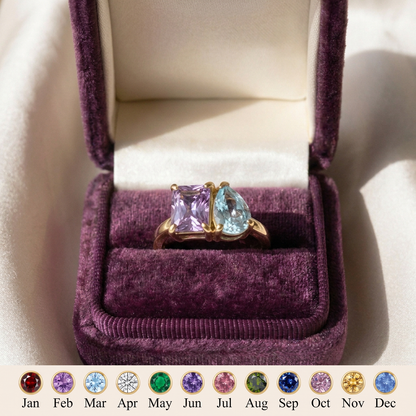 The two-birthstone ring slid into the slot of a plum velvet gift box with a plain cream satin lid