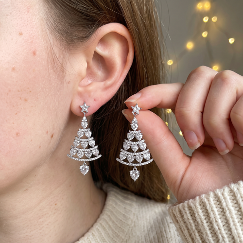 Silver Christmas tree drop earring worn, the second earring held up by its star