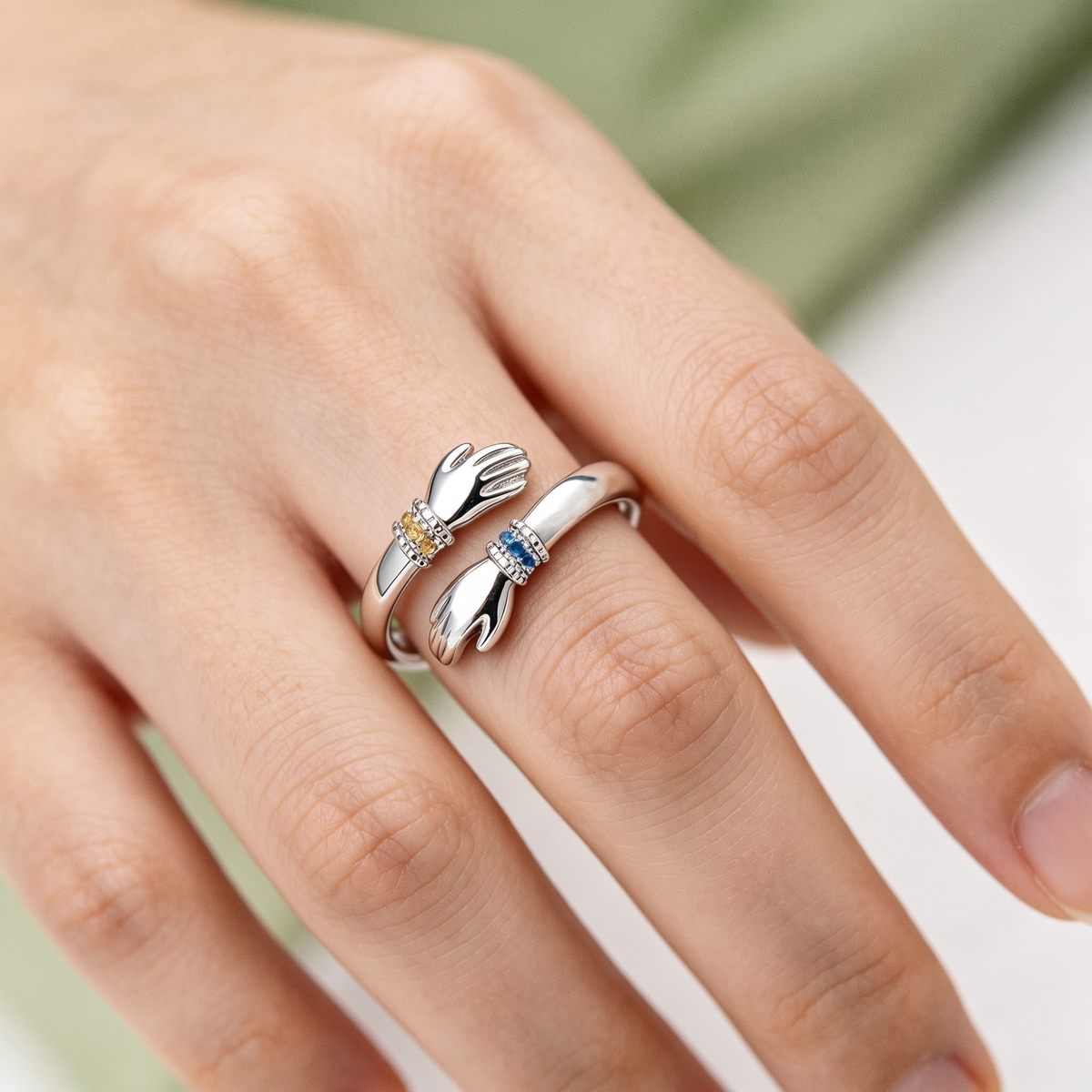 The silver hug ring worn on a finger