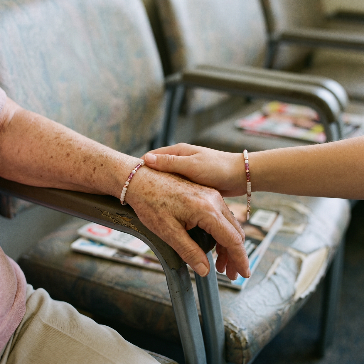 Two hands holding, the older one wearing the bracelet