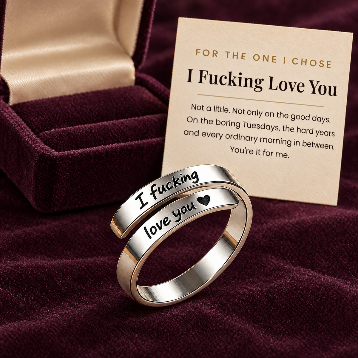 The silver ring in front of an open plum gift box and its card