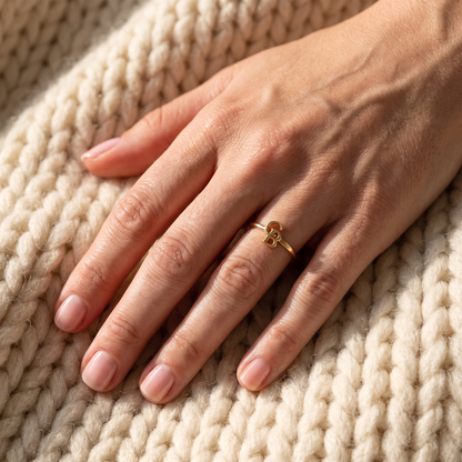 The gold ring worn on a hand resting on a knit blanket