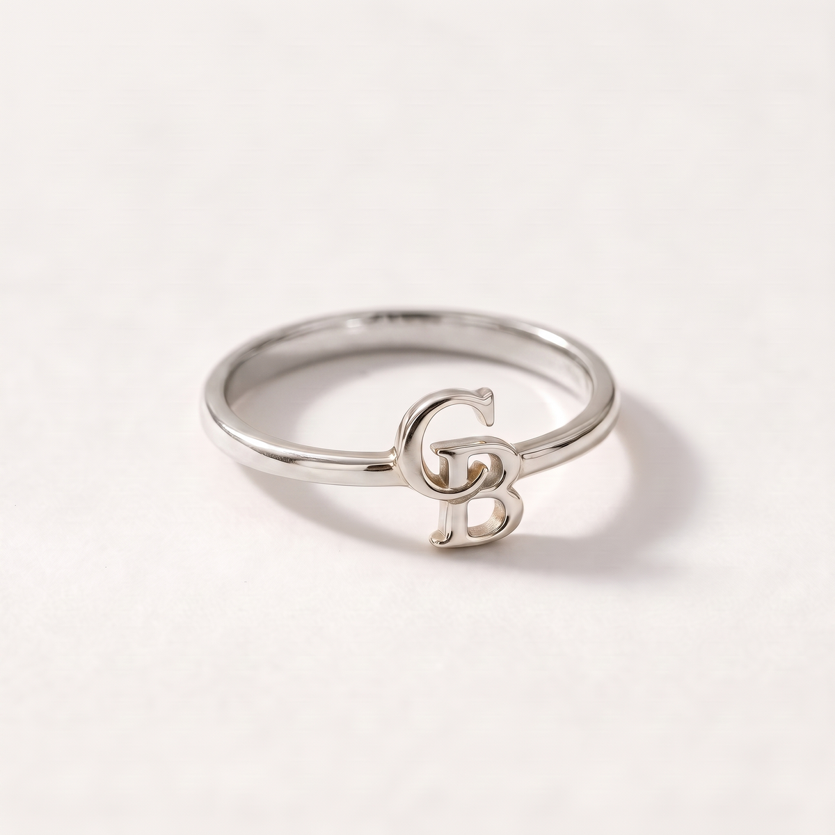 Silver ring with two interlocking serif initials