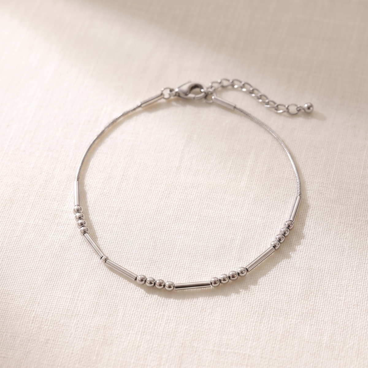 The silver Morse code chain bracelet on linen