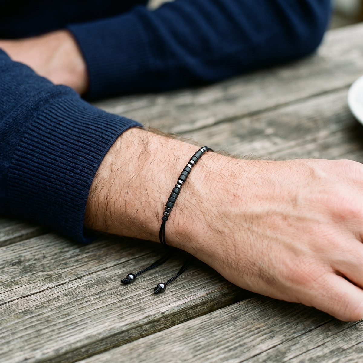 The black Morse code bracelet worn on a man's wrist