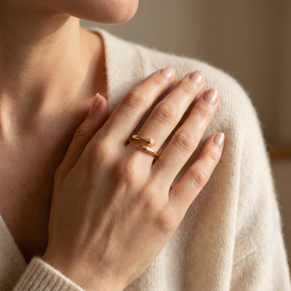 Woman wearing the dainty gold hug ring, two little arms hugging her finger