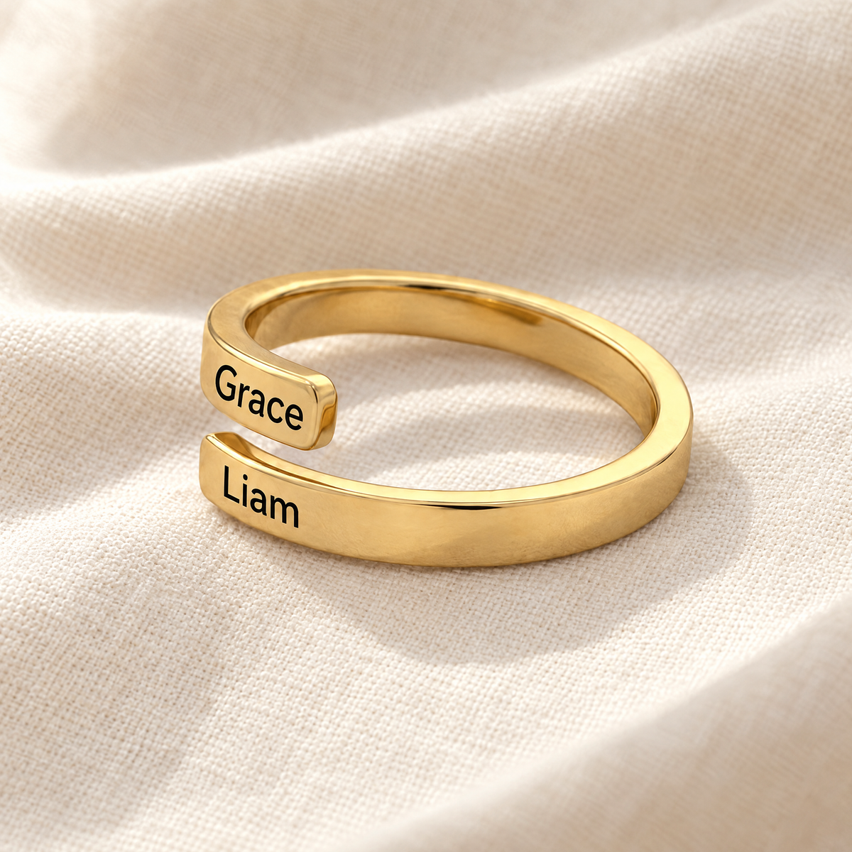 Gold open wrap ring engraved Grace and Liam on ivory linen
