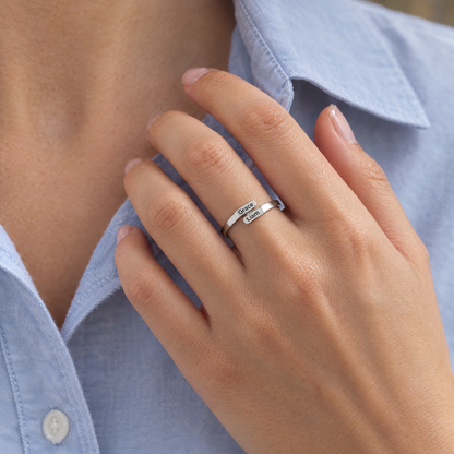 The silver ring worn on a hand resting on a blue shirt collar