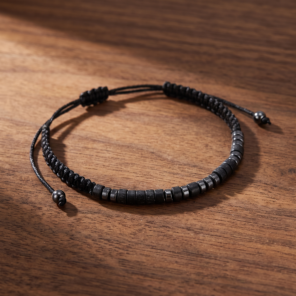 The black Morse code bracelet lying flat on walnut wood