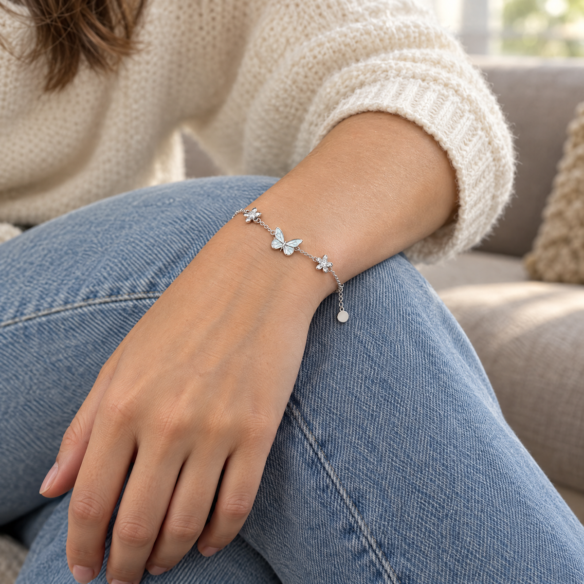 The butterfly bracelet worn in daylight, a hand resting on a knee in light blue jeans