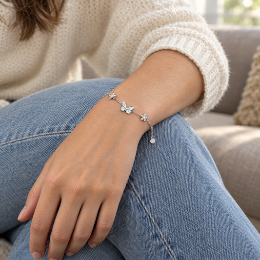 The butterfly bracelet worn in daylight, a hand resting on a knee in light blue jeans
