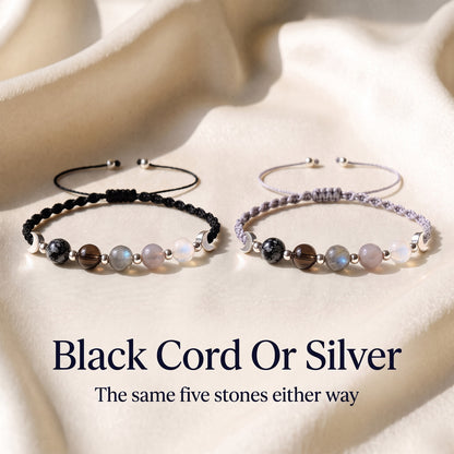 The black cord and the silver cord versions of the bracelet side by side on ivory satin, with the words Black Cord Or Silver