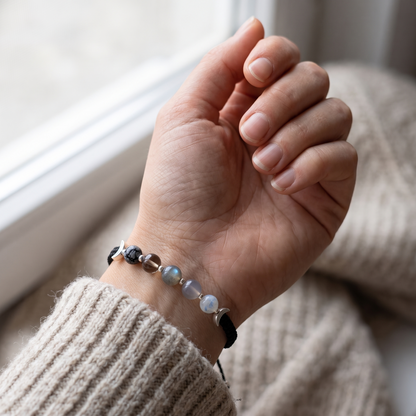 Moon phases crystal bracelet worn on a wrist over a knitted sleeve