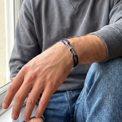 The bracelet worn by a man in a grey sweatshirt, the two linked names on top of his wrist