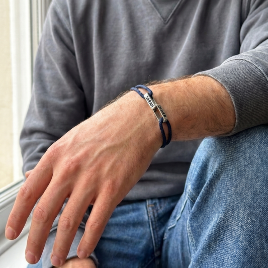 The bracelet worn by a man in a grey sweatshirt, the two linked names on top of his wrist