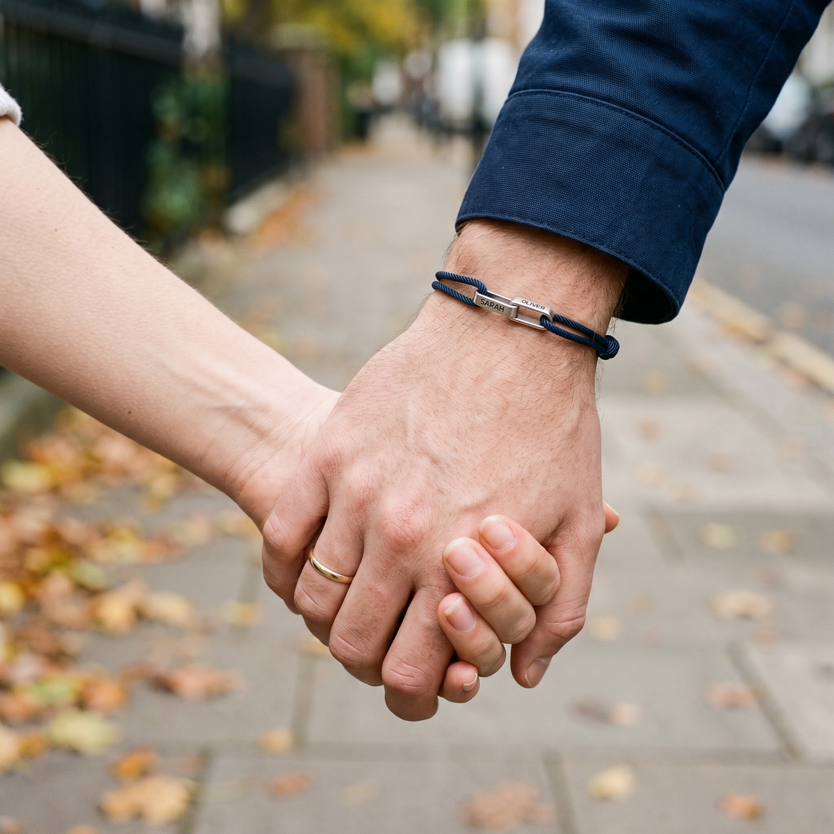 A couple holding hands on an autumn street, the bracelet on his wrist